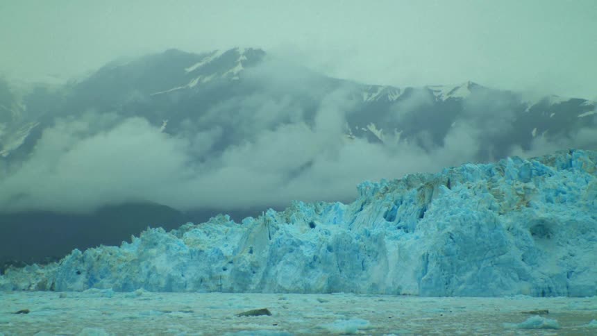 Slushy water borders glacier with foggy mountains in the background