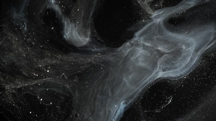 Abstract closeup of oil and water or black and white paint slow movements and some glitter