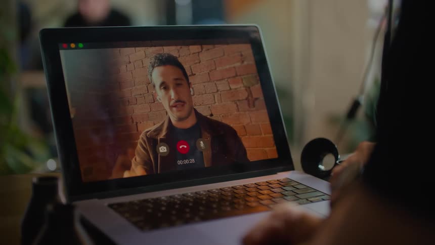 Man holding object meets with another man via video meeting on a laptop