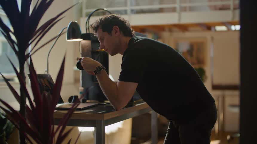 Man with black t shirt and jeans uses laptop at the office
