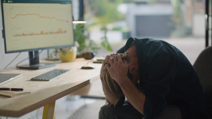 A young man is sitting down in the office and doesnt look happy
