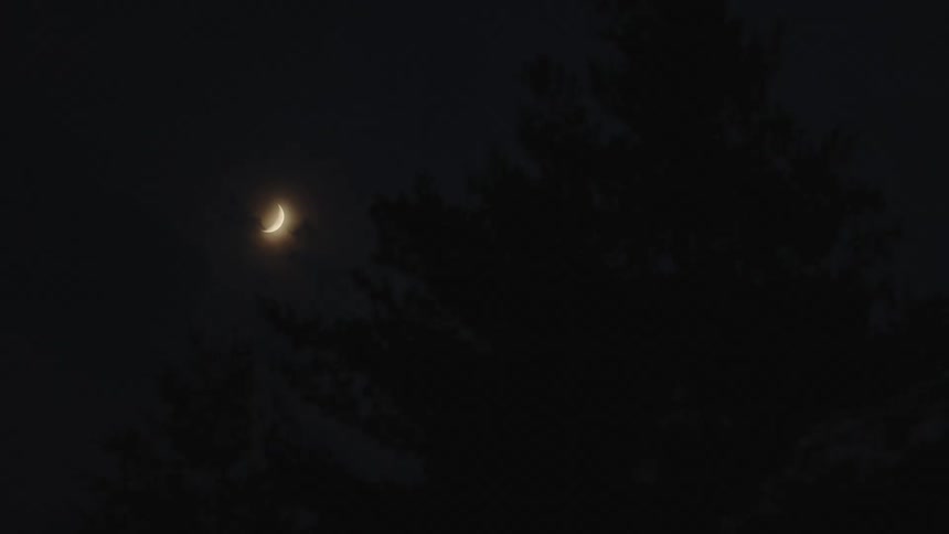 Nighttime sky black with crescent or new moon and stars not visibile