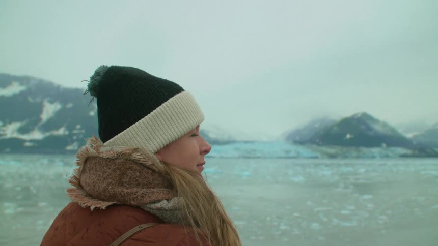 A woman is standing outdoors wearing a winter hat