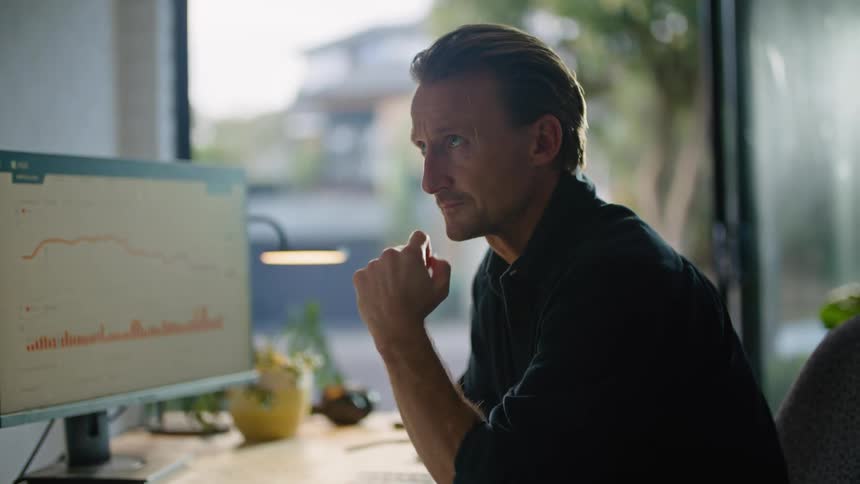 Businessman in black shirt sits at desk thinking carefully about idea at the office