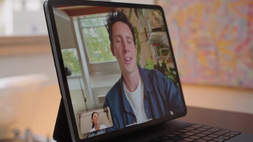 Woman in white shirt makes video call with man wearing blue shirt on tablet