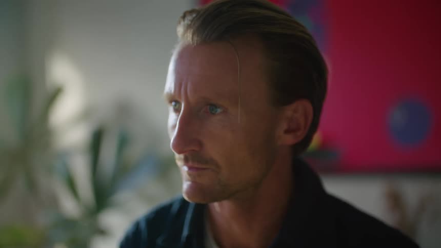 A man leans back and runs his heads through his hair