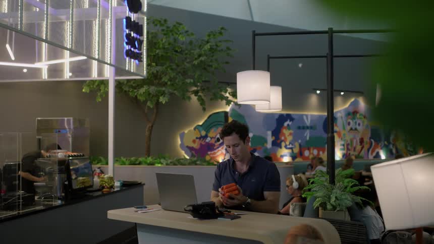 Businessman with dark blue shirt sits at desk using laptop at the office