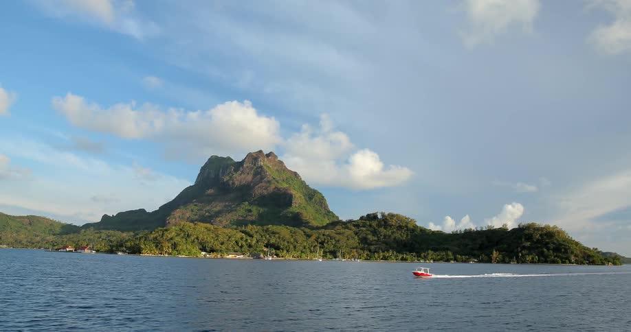 Boats sail in the water by an island
