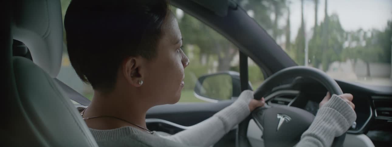 A woman drives down a neighborhood street