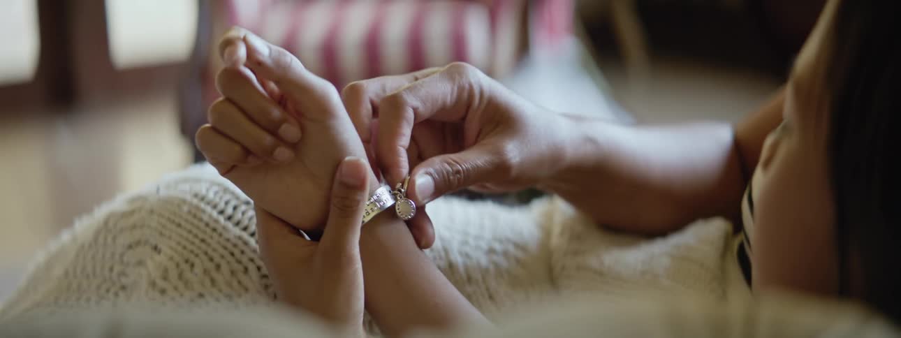 Mother fastens charm bracelet on daughters wrist