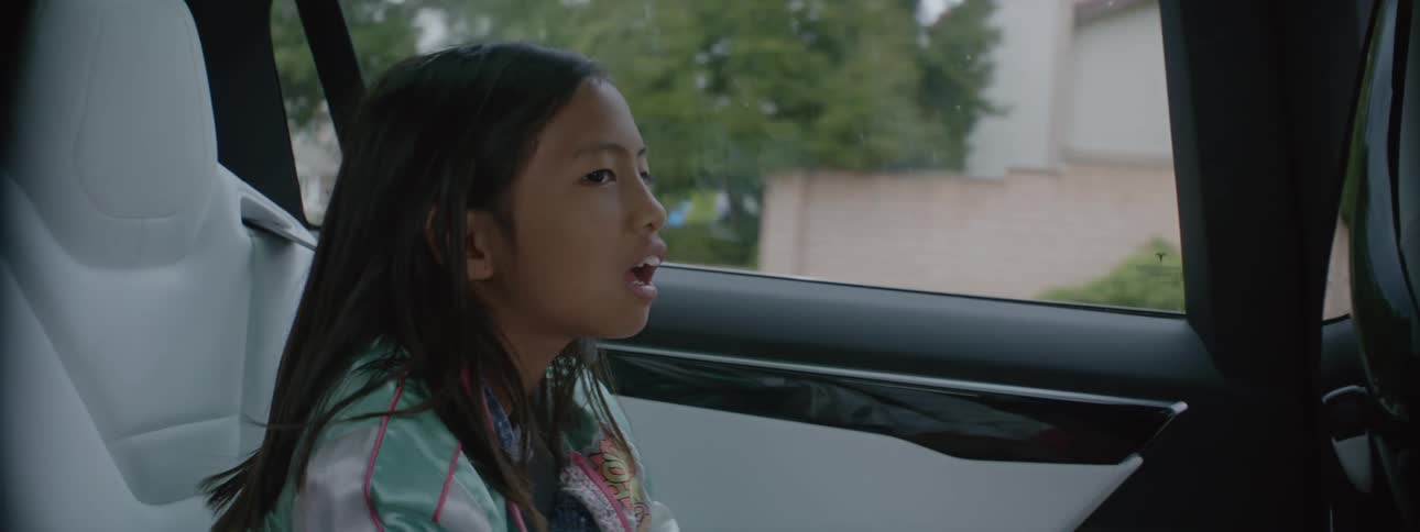 A young kid is in a car while someone else is driving it