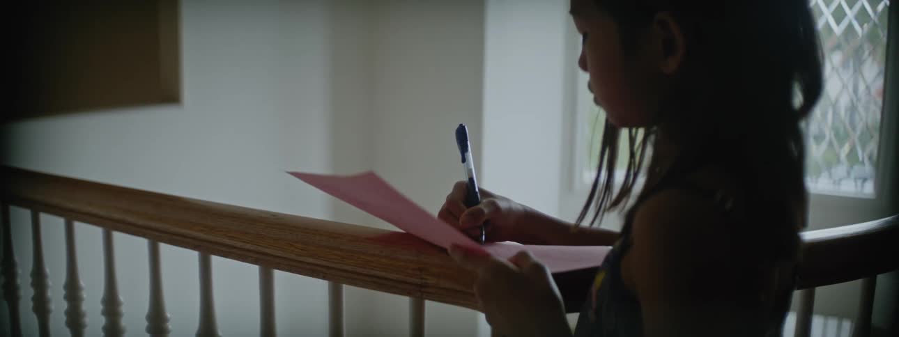 Young kid is writing something down inside of her house