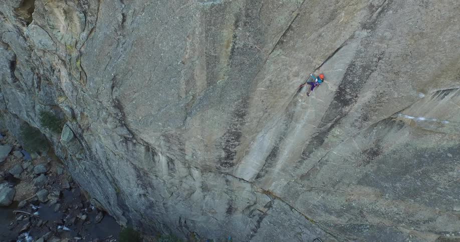 Aerial view of a mountaineer climbing the rock face of a mountain at daytime