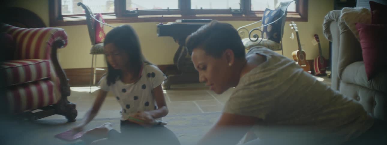 A girl and her mom play a board game on the floor at home