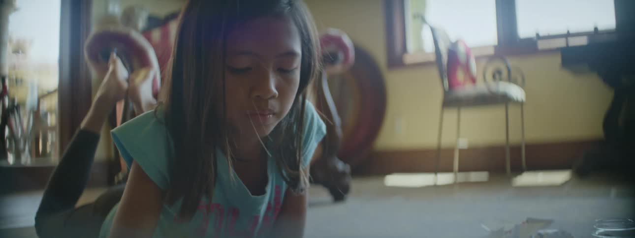 A young girl laying on the floor while creating something with paper