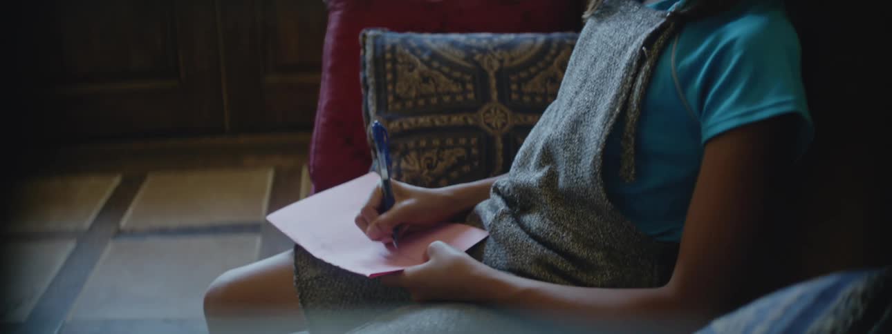 A girl takes notes while sitting on a pew