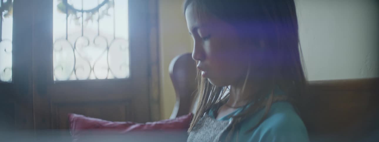 A young kid is sitting down on a couch in the middle of the day