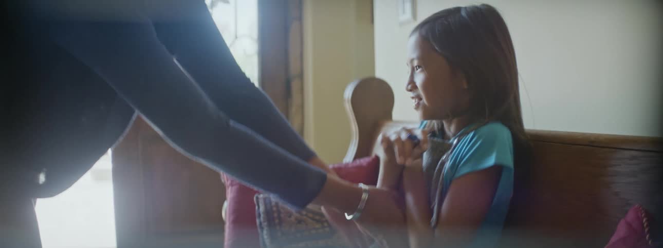 Mother tickles her daughter on a couch in the living room