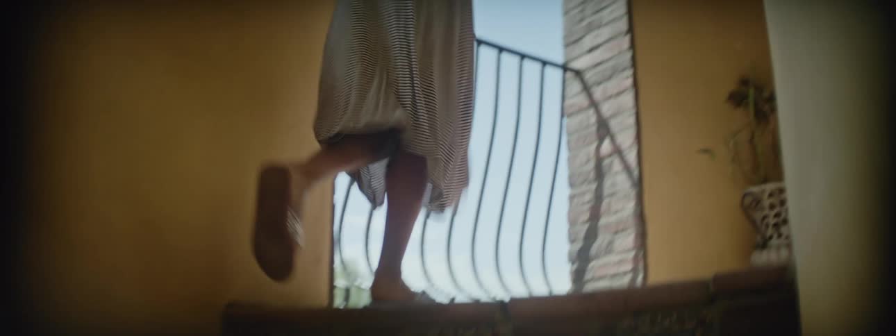 A girl runs up steps in her home carrying a paper windmill
