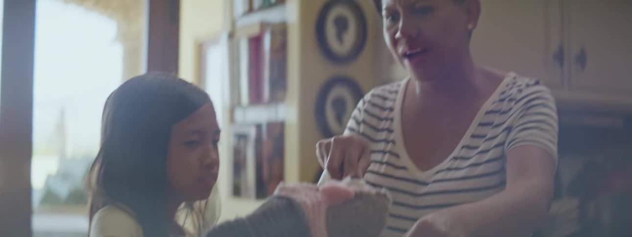 Grandmother and granddaughter in the kitchen laughing and baking cookies together granddaughter is playing with puppet