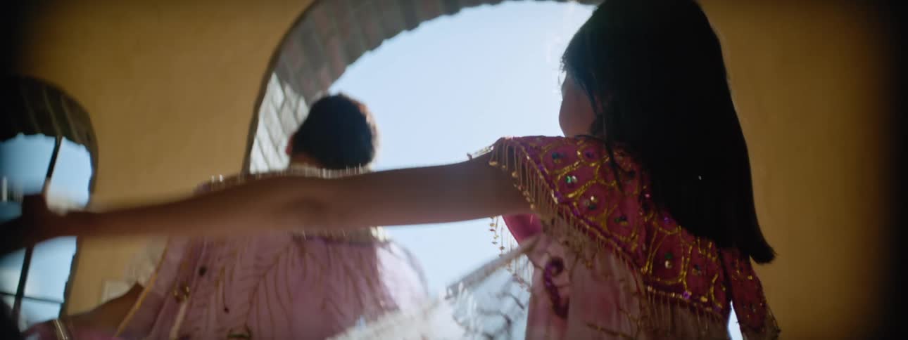 Close up of a girl waving her arms wearing a long dress learning to dance with her mother
