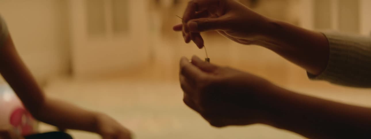 A mother and daughter make bracelets with metal beads on the floor at home