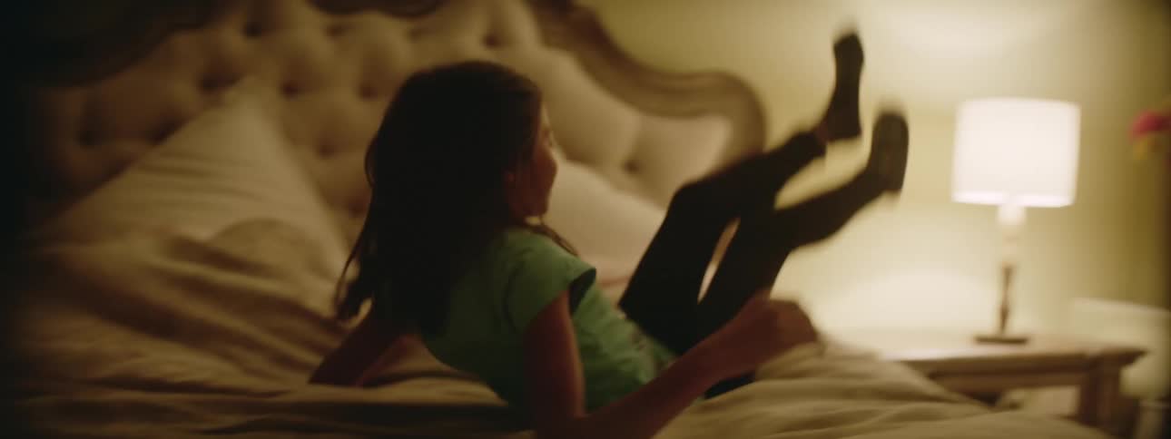 A young kid is playing on the bed and having fun