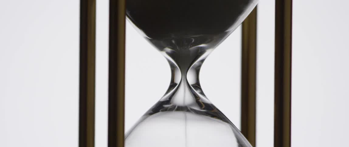 Sand is falling through an hourglass in a wooden frame