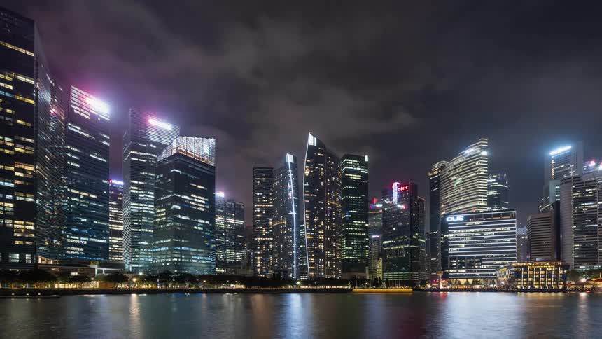 Clouds pass over skyscrapers on the coast at night in Singapore