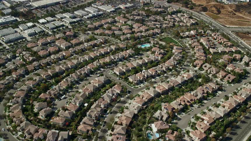 Aerial view of tract homes in Valencia California with trees grass and partly cloudy skies