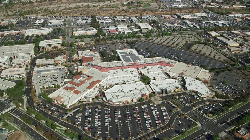 Aerial footage of Westfield Valencia Town Center in Santa Clarita California on a partly cloudy day orbiting around the busy shopping mall and retail center during the summer