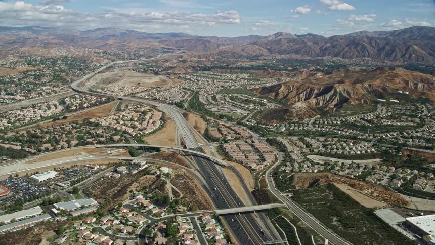 Aerial footage of traffic passing through a suburban area with mountains in the distance shot in Santa Clarita California