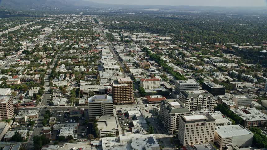 Aerial footage approaches Pasadena City Hall after flying over an office building in Southern California on a partly cloudy day