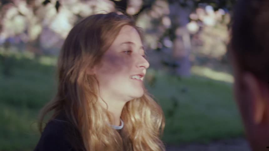 An upset teenage girl complains to a boyfriend at a park in the day