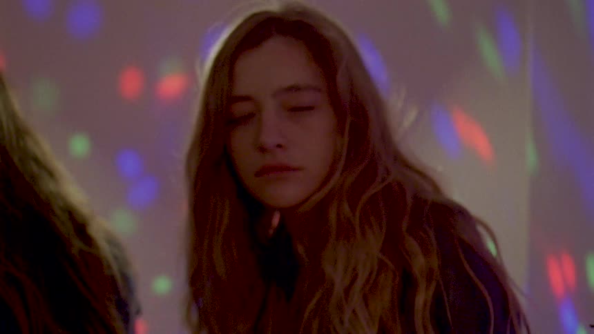 A woman looking lethargic moving her body as if dancing in a room with lights all over the wall