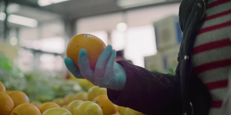 A woman grabbing and inspecting an orange
