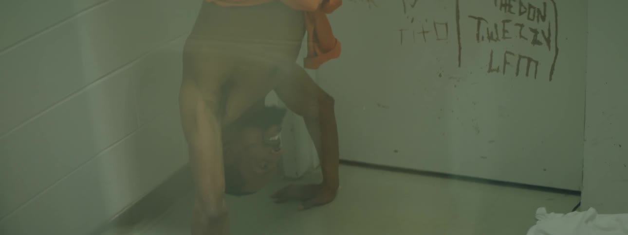 A prisoner is doing a handstand in a cell