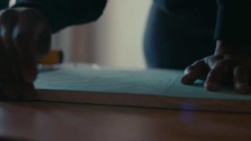A close up of a person sanding a board on a table