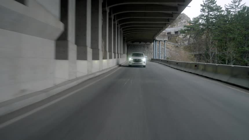 Man drives white vehicle under overhang near bridge