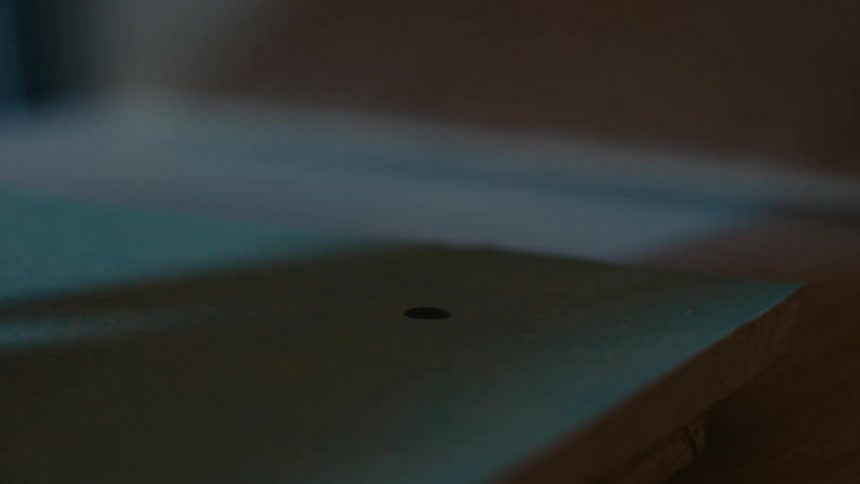 A close up of a person using a screw driver to drive a screw into a piece of wood