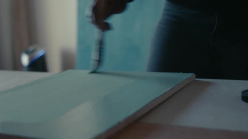 A person is painting a piece of furniture indoors