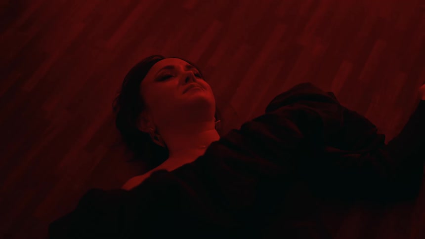Woman wearing a luxury dress opens laying on the floor of her apartment under red lights