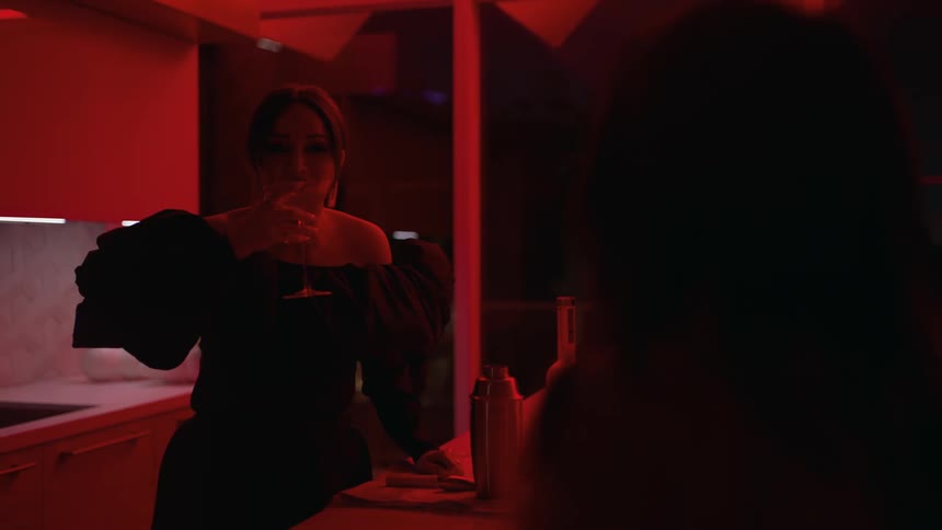 A young woman is drinking in her home at night time