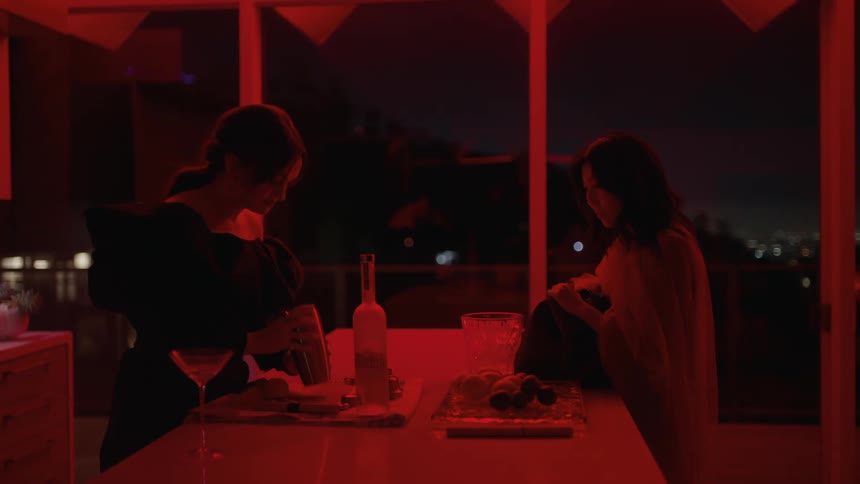 Two women talk while one serves drinks
