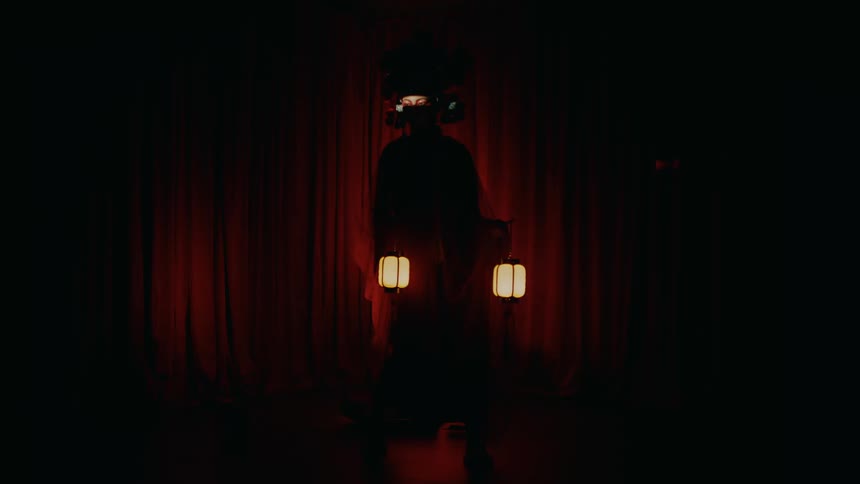 A woman stands on stage holding paper lanterns