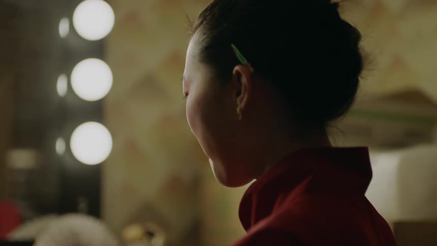 A womans reflection in a mirror and then focusing on her face as she smiles and laughs