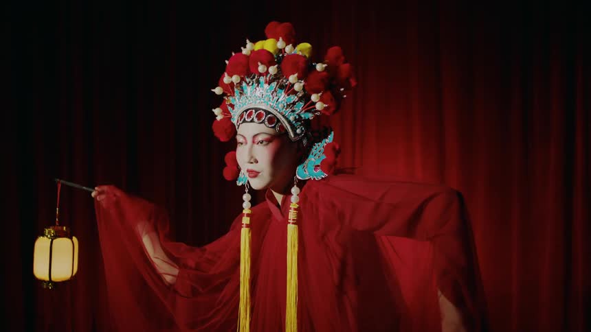 A woman wearing a red costume dancing on stage holding two lanterns in her hands