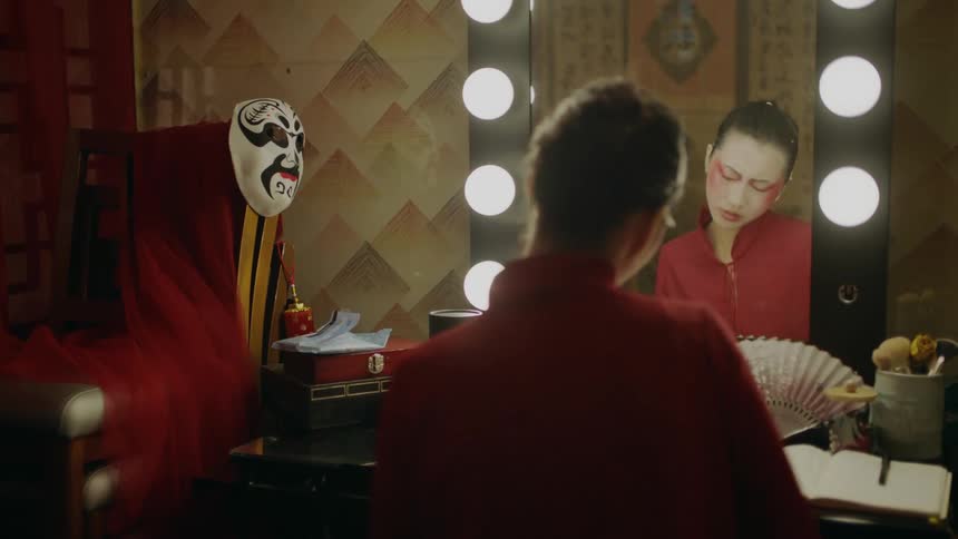 Actress sitting on a dressing room applies makeup for a chinese theatre performance