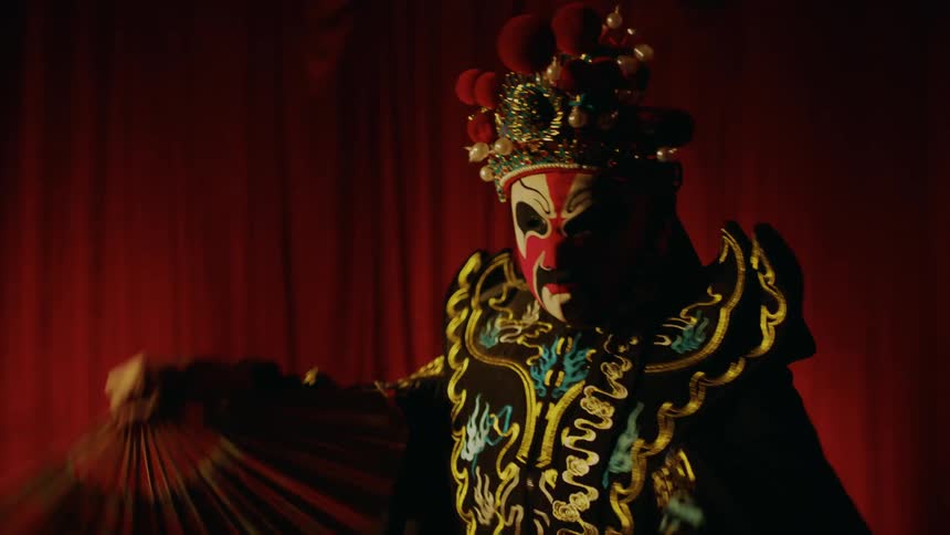 Actress on stage performing a bian lian chinese theatre dance in front of a red curtain