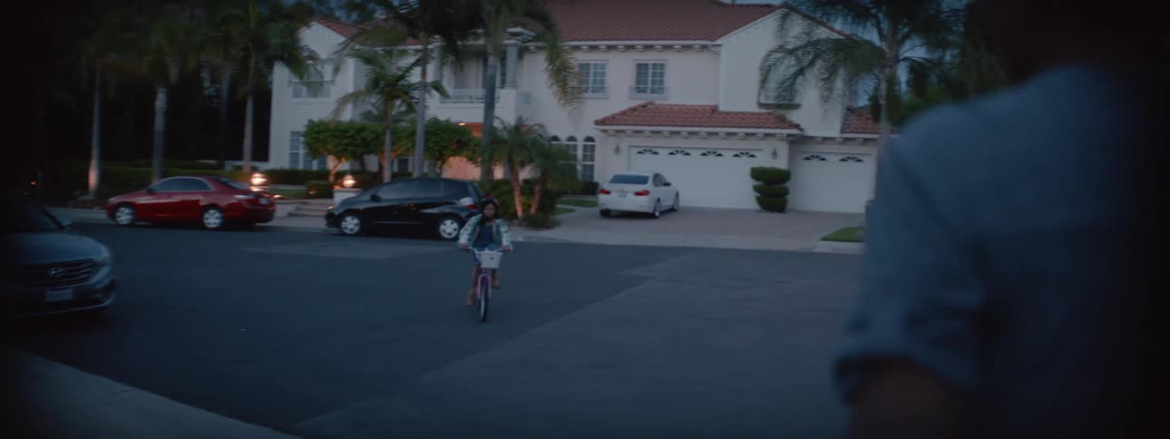 Mother smiles and watches daughter approach and ride around her on bicycle before she rides away again